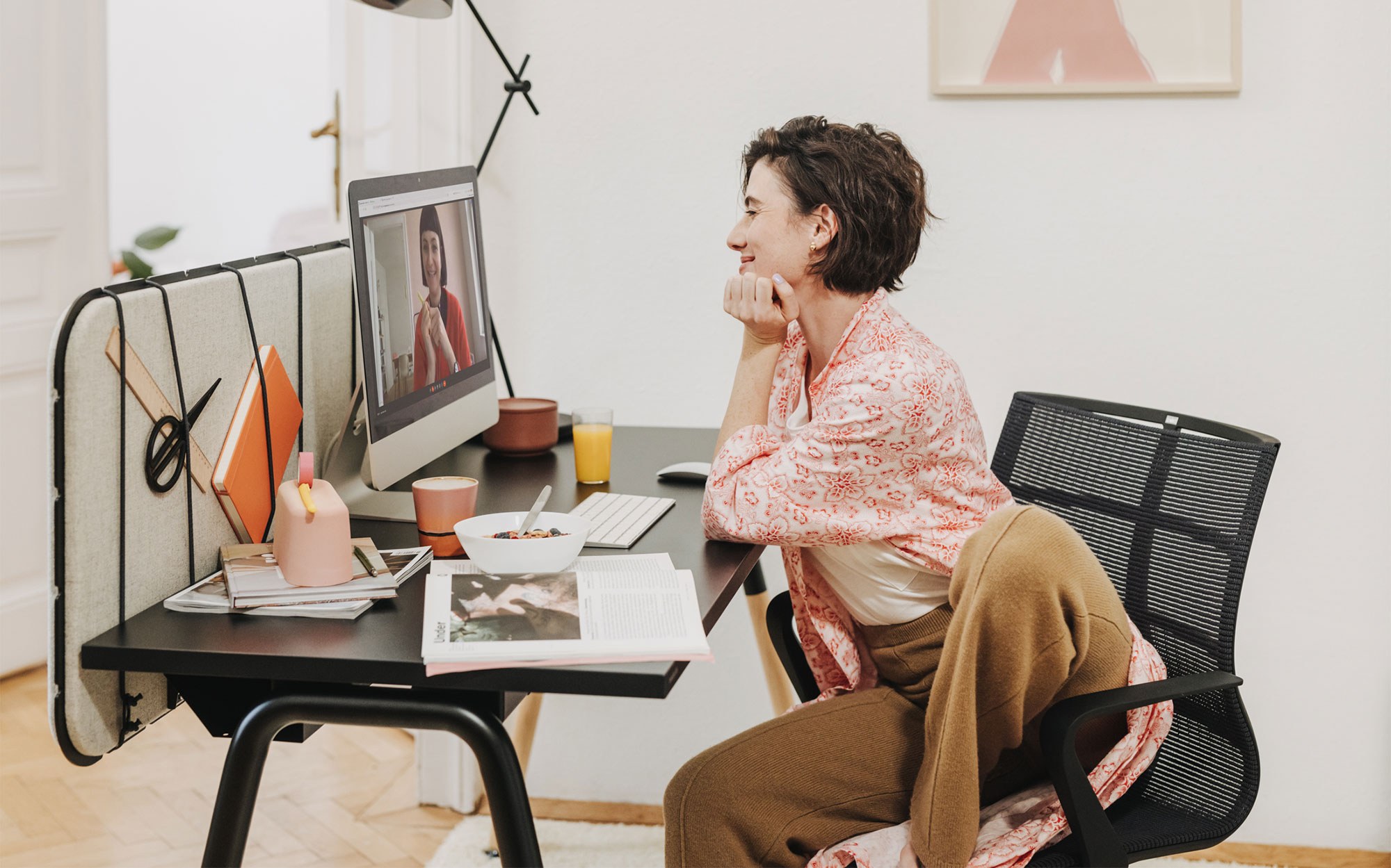 Eine Frau mit kurzen braunen Haaren sitzt an ihrem Schreibtisch und arbeitet am Computer.